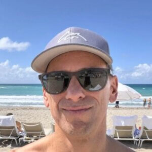 Man in sunglasses smiling at the beach