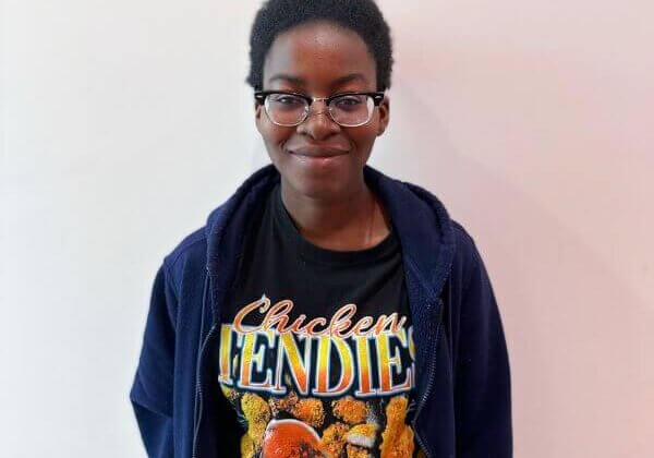 A student smiling with glasses against a white backdrop